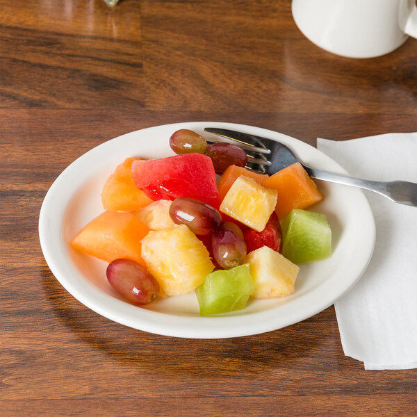 A CAC ivory china platter with a plate of fruit on a table.
