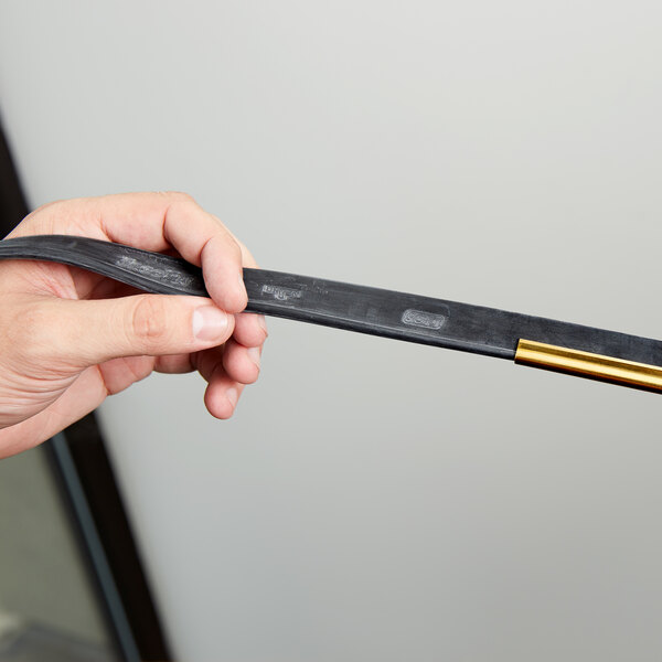 A hand holding a black and gold Unger squeegee blade.