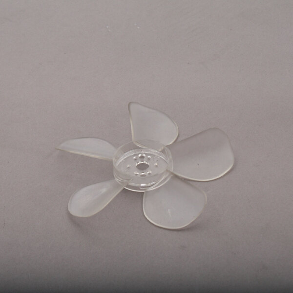 A clear plastic Delfield fan blade on a grey surface