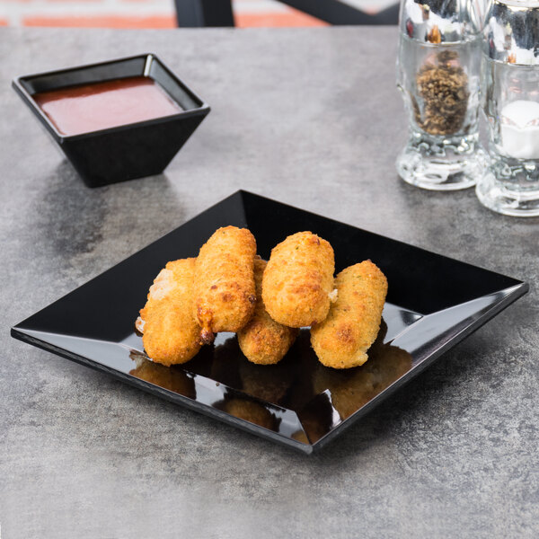 A black square plate with fried food on it.
