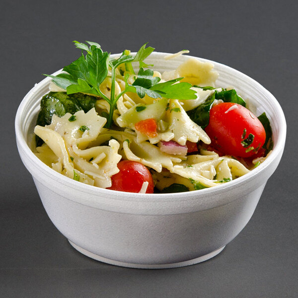 A Dart white foam bowl filled with pasta salad and vegetables.