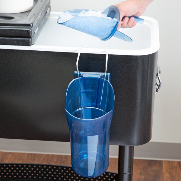 A hand using a San Jamar Saf-T-Ice scoop to fill a blue plastic container with ice.