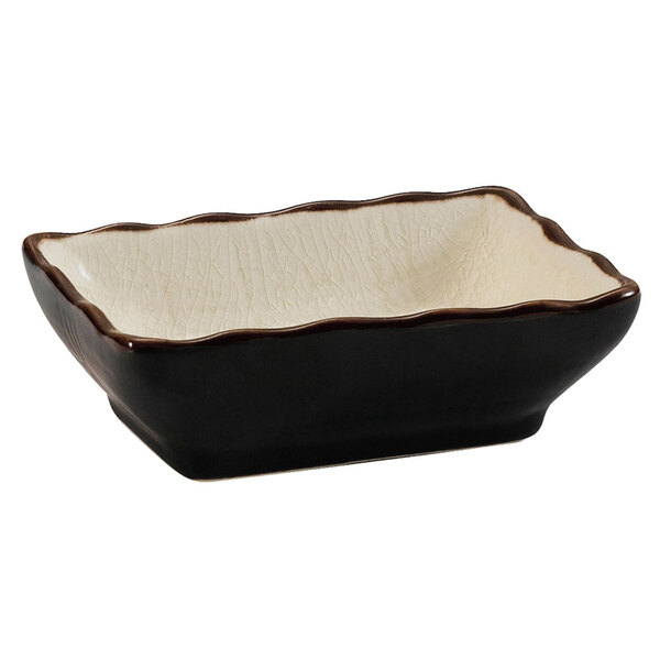 A black and white rectangular CAC stoneware sauce dish with a brown rim.