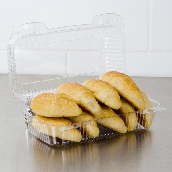A Dart clear plastic container filled with croissants.