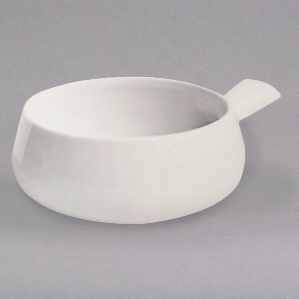 A Hall China ivory side handle soup bowl on a gray surface.