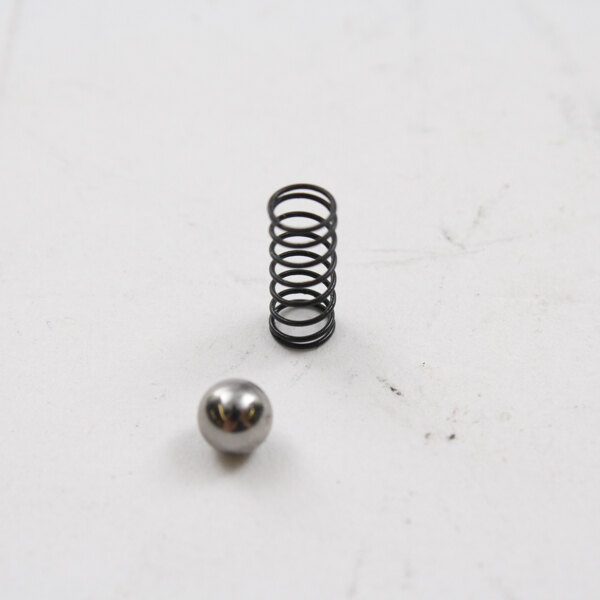 A silver metal ball and a spring on a white surface.