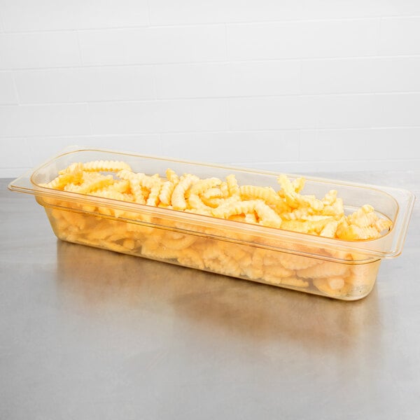 A Cambro amber plastic food pan filled with macaroni and cheese on a school kitchen counter.