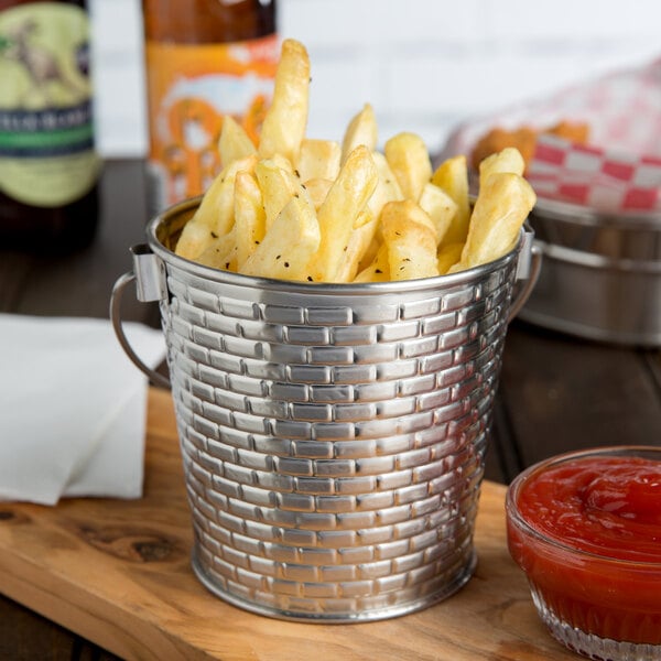 A Tablecraft stainless steel serving pail filled with french fries and a bottle of ketchup.