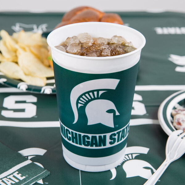 A Michigan State University plastic cup filled with soda and ice on a table.