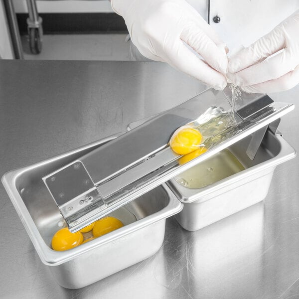 A person using the Bron Coucke stainless steel egg separator to separate an egg.