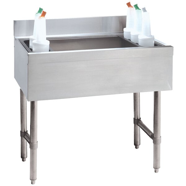 An Advance Tabco stainless steel underbar ice bin with a 10-circuit cold plate filled with ice and white containers.