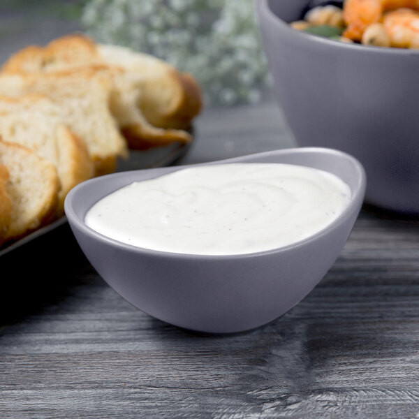 A close-up of a Libbey Driftstone granite porcelain bowl filled with white sauce next to a bowl of bread.