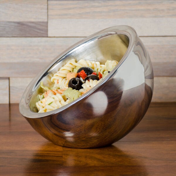 An American Metalcraft stainless steel bowl of pasta and olives on a wood surface.
