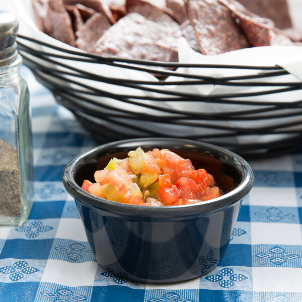 A table with a bowl of salsa and a bowl of meat.