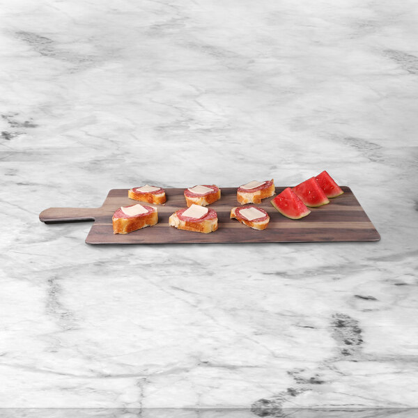 An Elite Global Solutions rectangular faux hickory wood melamine serving board with slices of watermelon and butter on it.