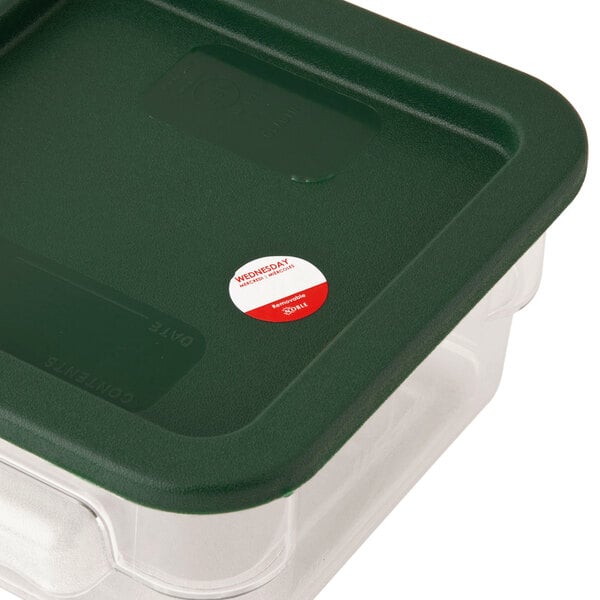 A plastic container of Noble Products Wednesday food labeling stickers with a green lid on a counter.