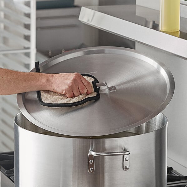A person using a yellow glove to clean a Choice pot lid.