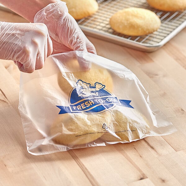 A person wearing gloves using a Printed Plastic Deli Saddle Bag to put cookies inside.
