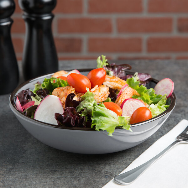 An Elite Global Solutions Mojave gray crackle bowl filled with salad with radishes and tomatoes on a table.