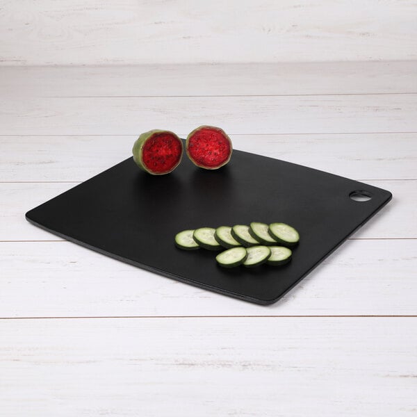 A black rectangular Elite Global Solutions serving board with sliced cucumbers on it.