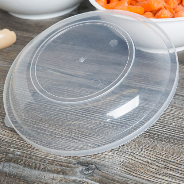 A plastic container with a Fineline clear plastic lid on a pile of carrots.