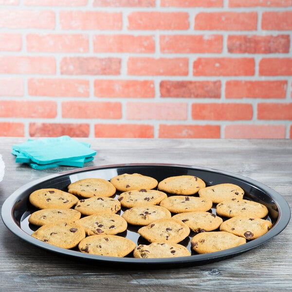 A plate of chocolate chip cookies on a black Fineline plastic catering tray on a table.