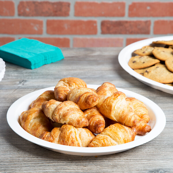 A white Fineline high rim plastic catering tray with croissants and cookies on a table.