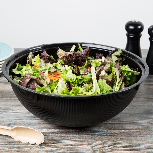 A black Fineline high profile plastic catering bowl filled with salad on a table.