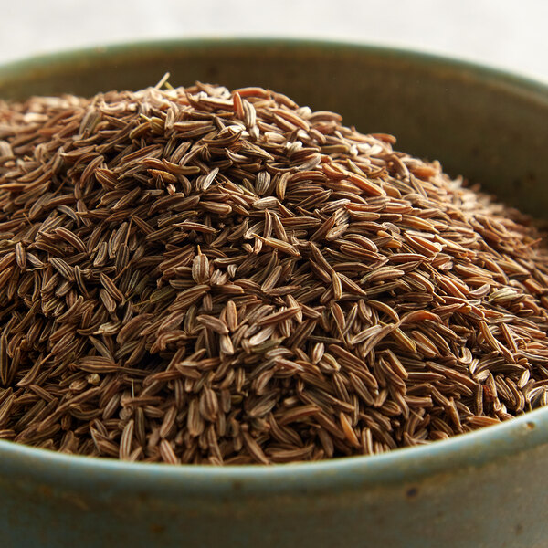 A white bowl filled with Regal caraway seeds on a table.