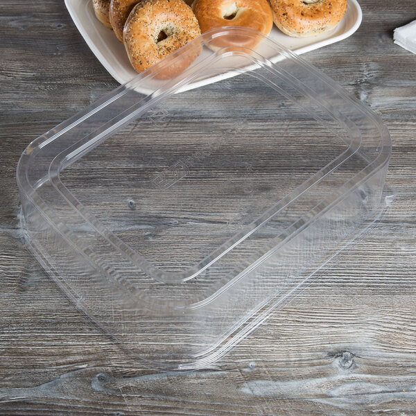 A clear plastic Eco-Products lid on a tray of bagels with a bagel on top.