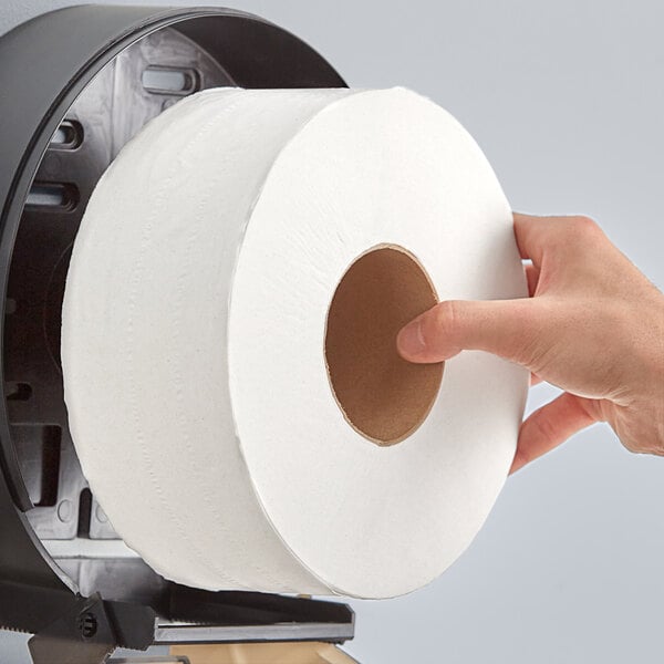 A hand holding a Lavex jumbo toilet paper roll.