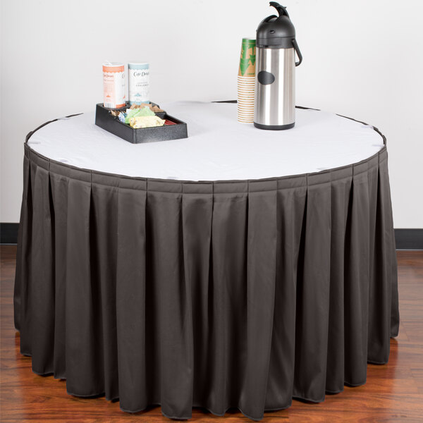 A table skirt with a black tablecloth on a table with a tray of coffee cups.