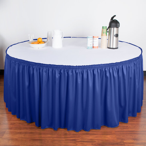 A table with a royal blue shirred pleat table skirt with velcro clips.