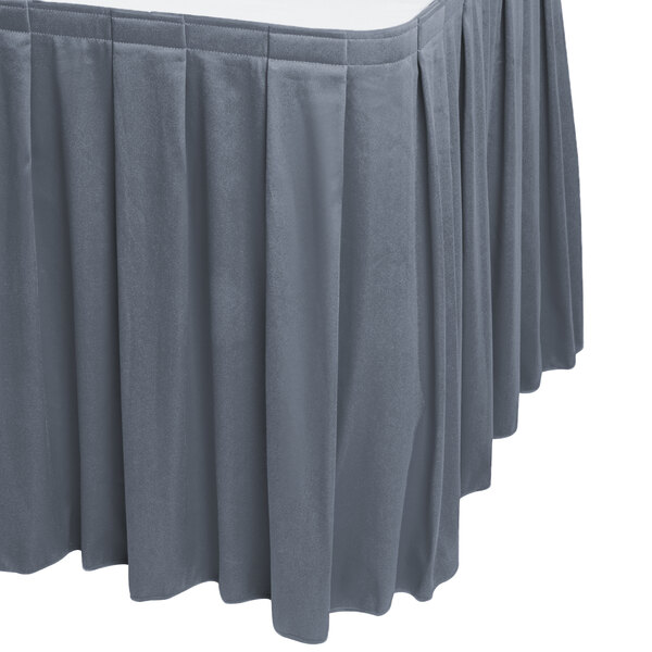 A slate blue Snap Drape box pleat table skirt on a table with pleated edges.