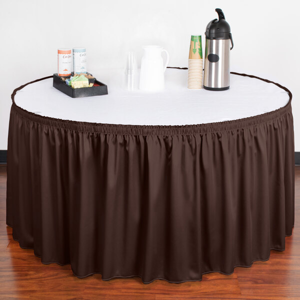 A table with a brown table skirt on it and a tray of coffee cups.