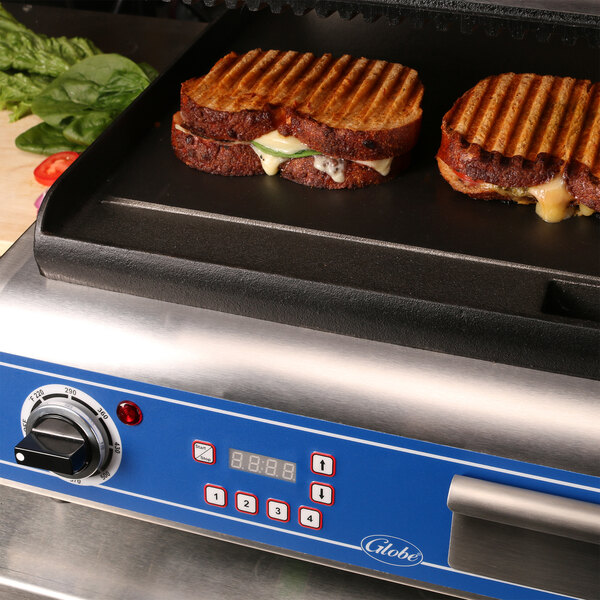 A Globe commercial panini grill with two grilled sandwiches on it.