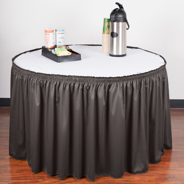 A table with a Snap Drape charcoal shirred pleat table skirt on it with a tray of food.