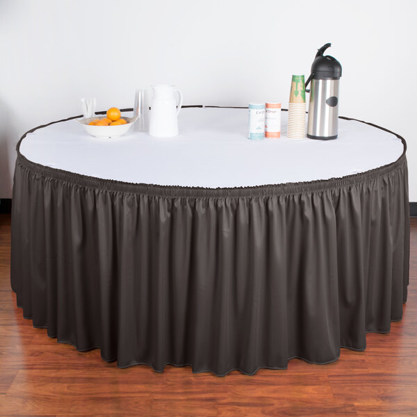 A table with a charcoal shirred pleat skirt on it.