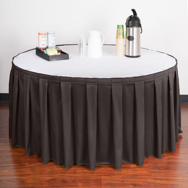 A table with a black Snap Drape table skirt with a tray of coffee cups.