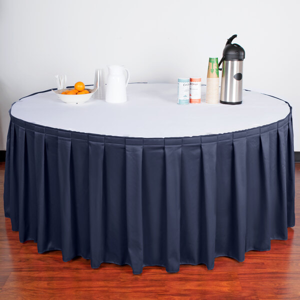 A table with a navy Snap Drape box pleat table skirt on it.