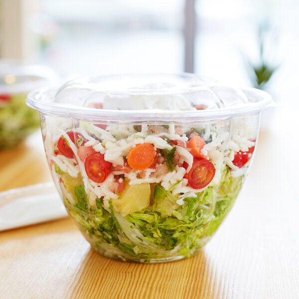 A salad in a 48 oz. clear compostable plastic salad bowl with a lid.