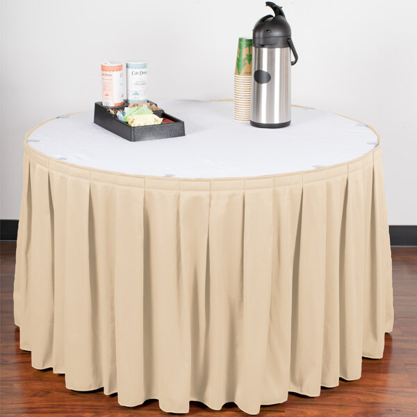 A table skirt with velcro clips on a table with a white tablecloth and a tray of coffee cups.