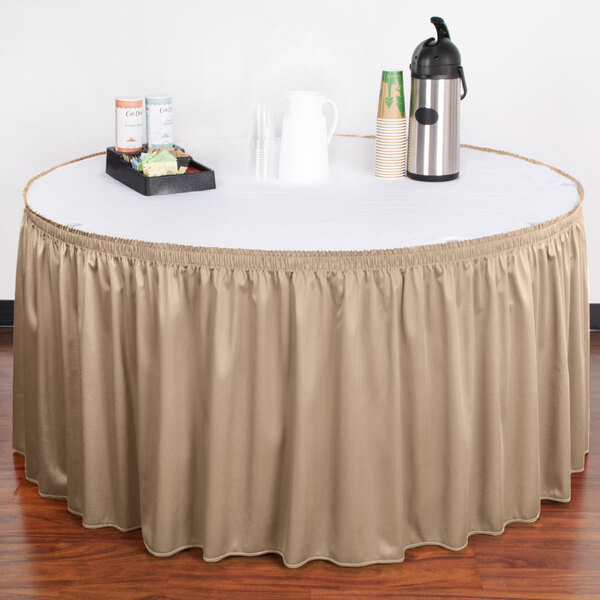 A table with a beige Snap Drape table skirt and coffee cups on a tray.
