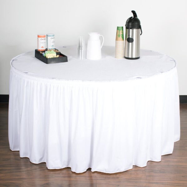 A table with a Snap Drape white shirred pleat table skirt on a white table with a tray of coffee cups.