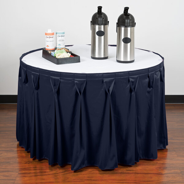 A table with a navy Snap Drape table skirt and containers on it.