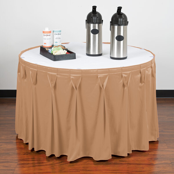A table with a Snap Drape Sandalwood table skirt on it with a tray of food.