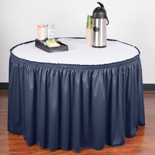 A table with a navy shirred pleat table skirt with velcro clips.