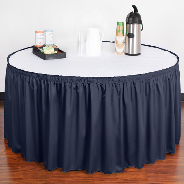 A table with a navy blue Snap Drape table skirt on it.