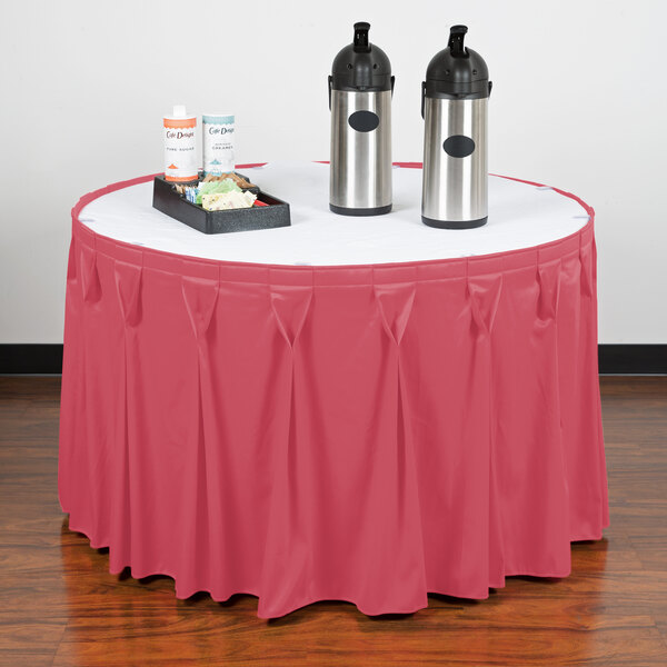 A table with a Snap Drape Dusty Rose table skirt with Velcro clips on it and a couple of containers.