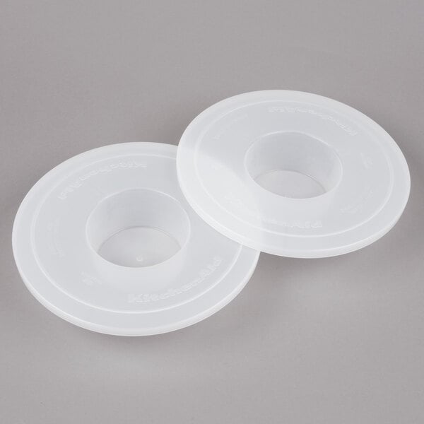 Two white plastic KitchenAid mixer bowl covers.